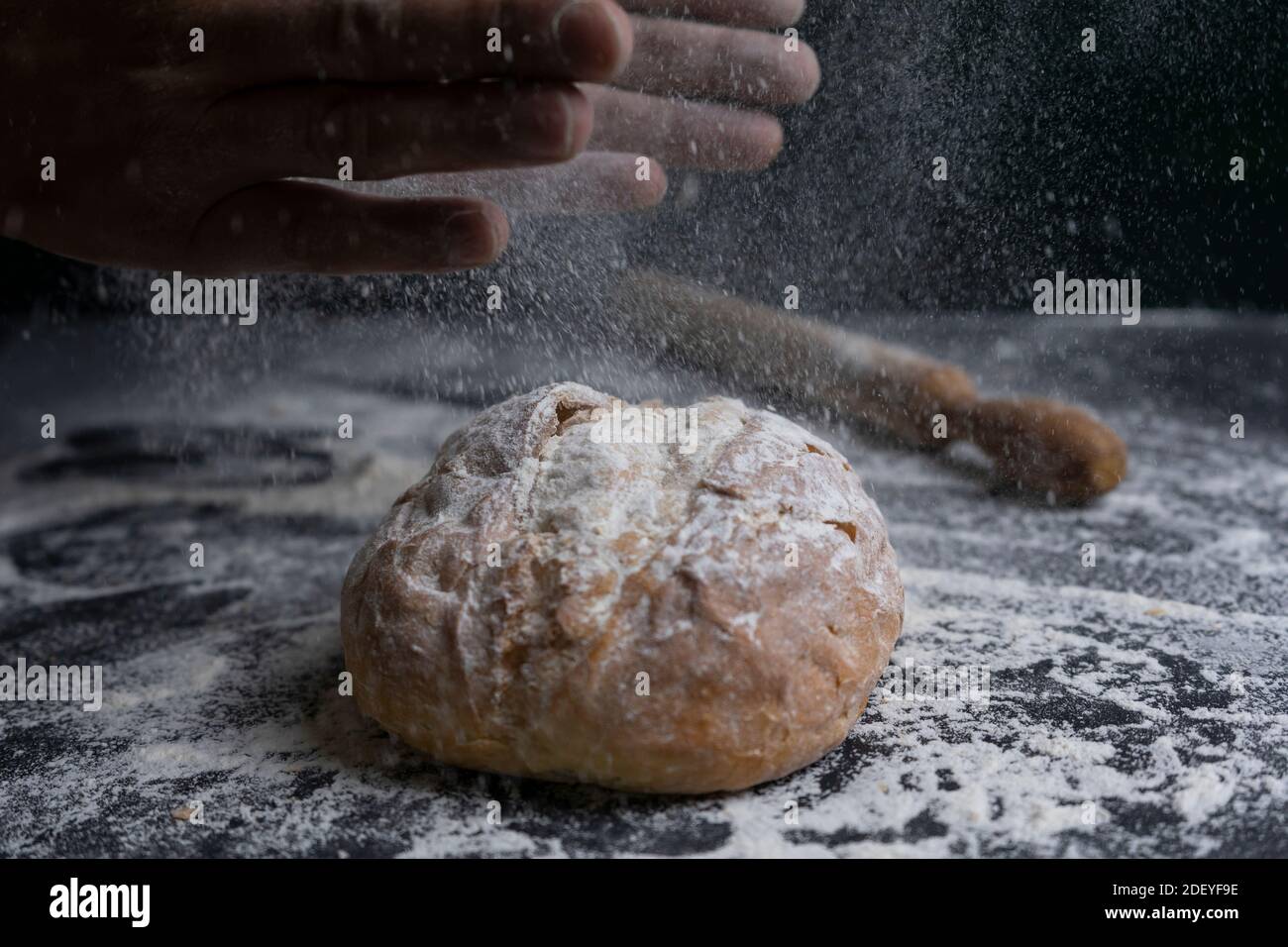 Baker klatschen Hände mit Mehl Spritzer auf frisches Brot.Bakery Konzept Lifestyle mit Rollen auf mehligen dunklen Hintergrund. Stockfoto