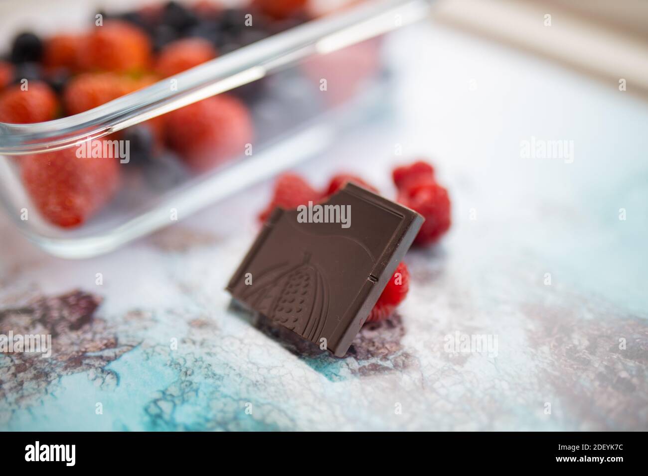 Zerstoßen Sie Schokolade und Himbeeren auf einem bunten Tischset Stockfoto