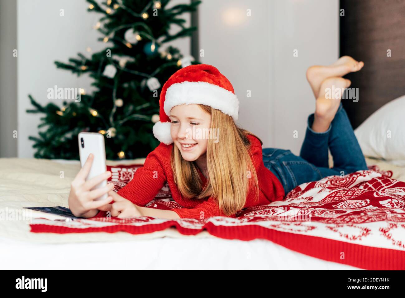 Mädchen in einem Weihnachtsmann Hut spricht auf einem Video-Chat am Telefon. Stockfoto