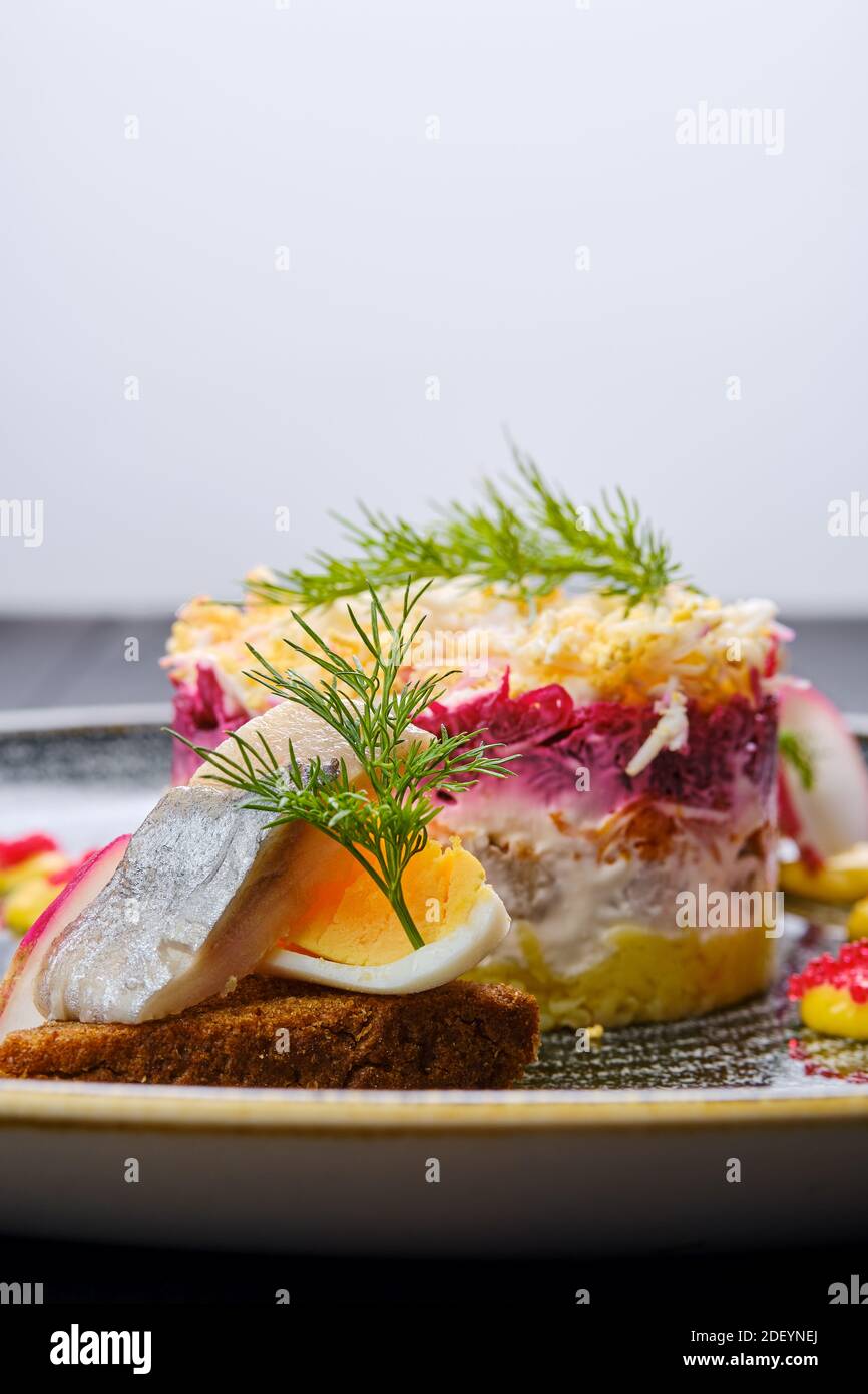 Nahaufnahme von Hering geschichteten Salat mit einem dekoriert Ein Viertel eines gekochten Eies und ein Stück Hering Stockfoto