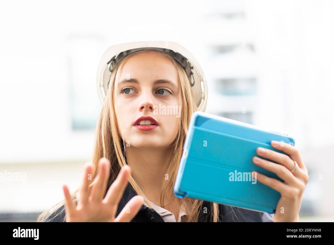 Junge Ingenieurin weiblich mit Tablet und Arbeitshelm draußen Stockfoto