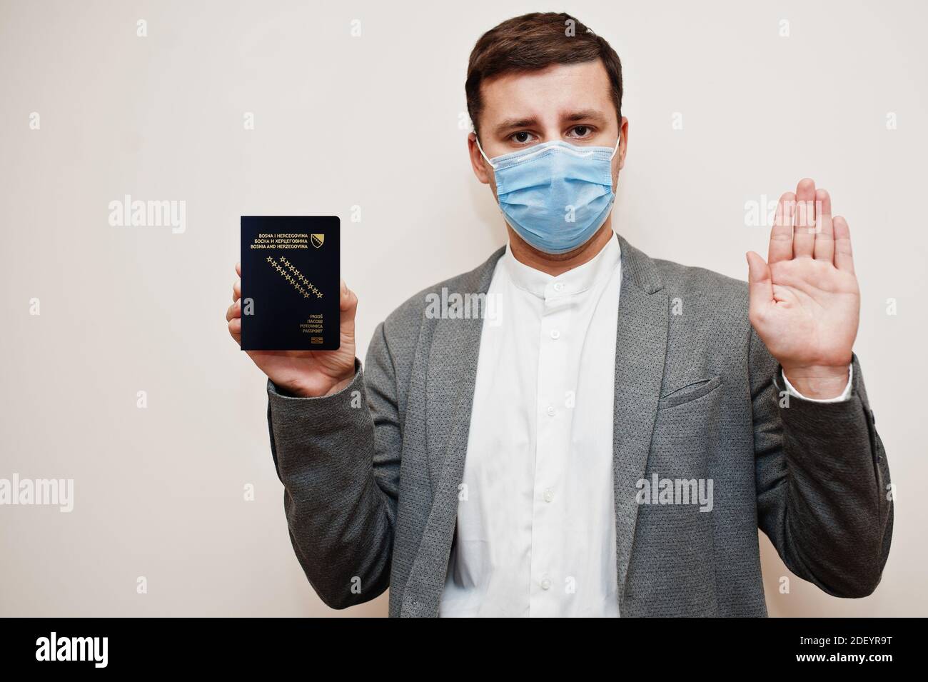 Europäischer Mann in formeller Kleidung und Gesichtsmaske, zeigen Bosnien und Herzegowina Pass mit Stoppschild Hand. Coronavirus-Lockdown im europäischen Länderkonzept. Stockfoto