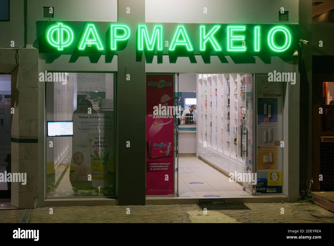 Thessaloniki, Griechenland Griechisch geöffnet Apotheke Eingang. Blick von außen auf den hellenischen Pharmaladen mit beleuchtetem grünen Schild und Schaufenster. Stockfoto