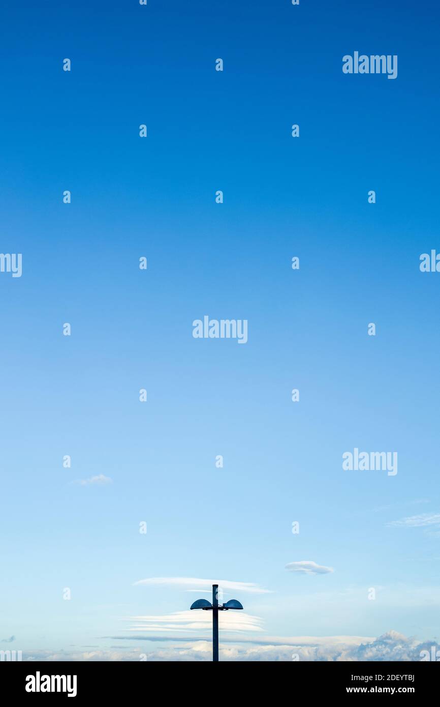 Minimalistisches Bild von Lampost, linsenförmigen Wolken und blauem Himmel, Puerto Santiago, Teneriffa, Kanarische Inseln, Spanien Stockfoto