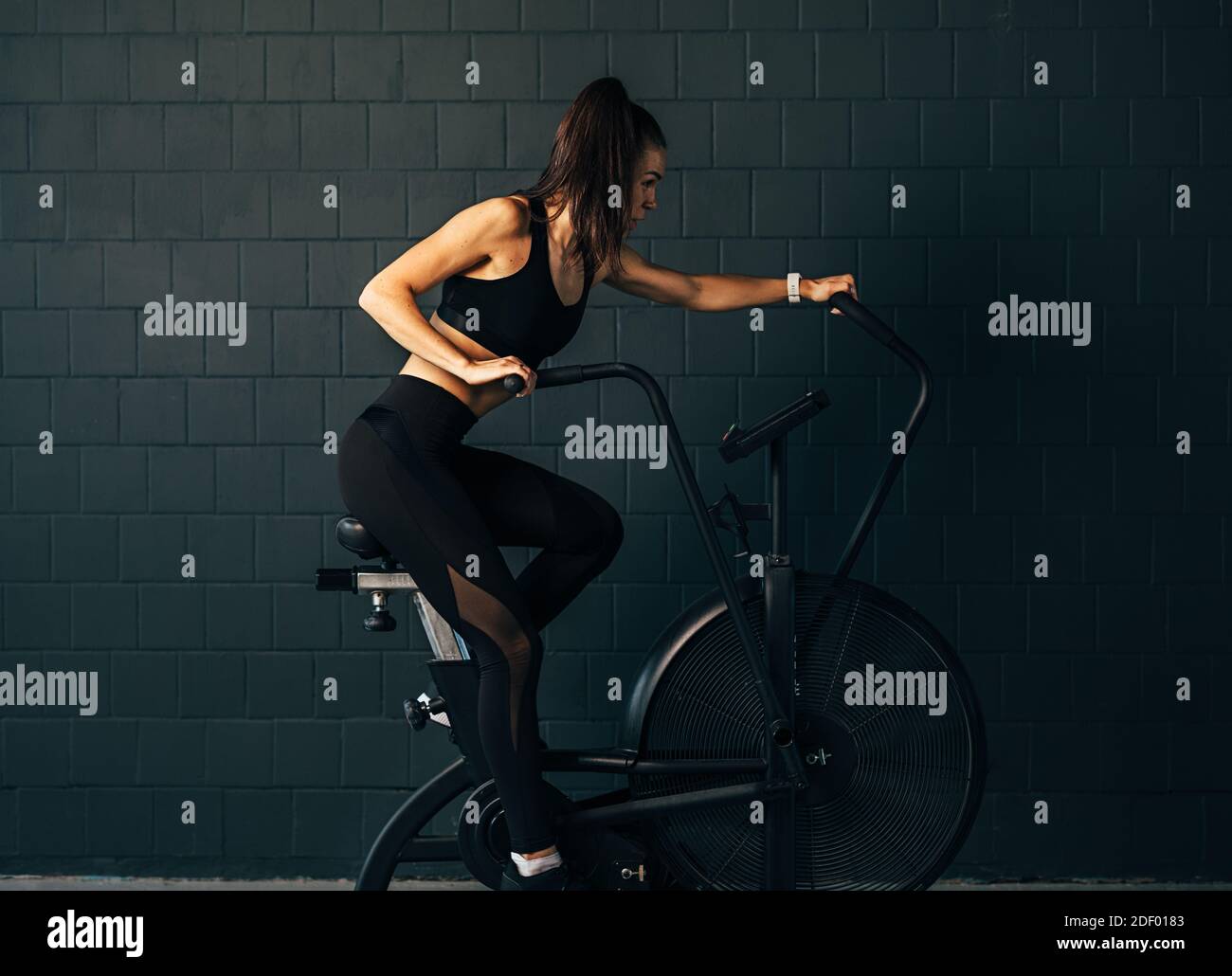 Seitenansicht einer muskulösen jungen Frau, die intensiv trainiert Auf dem Luftfahrrad Stockfoto