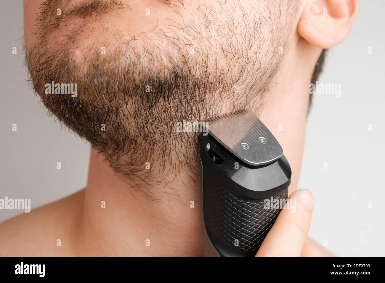 Mann rasieren Bart und Hals mit einem elektrischen Rasiermesser.  Morgendliche Routine. Bart mit einem Trimmer trimmen Stockfotografie - Alamy