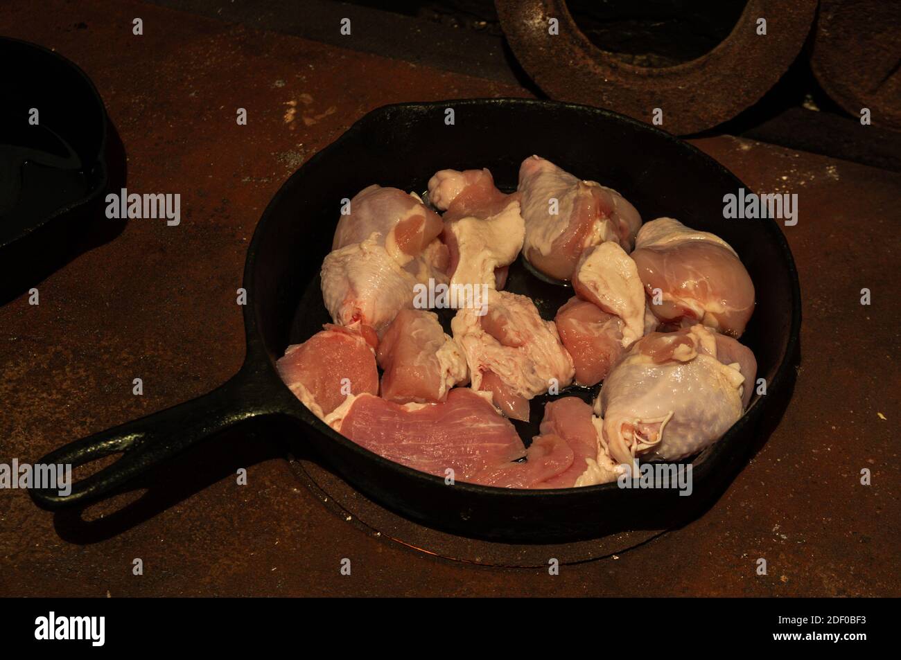 Bereiten Sie das Fleisch in einer gusseisernen Pfanne vor, die auf einem rostigen Holzofen steht. Hochwertige Fotos Stockfoto