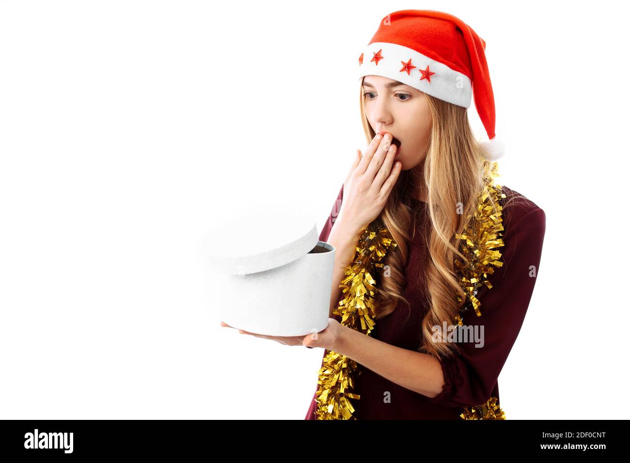 Geschockt Mädchen in santa Hut, sieht in einer Geschenkbox, überrascht, auf einem weißen Hintergrund. Ein Weihnachtsgeschenk Stockfoto