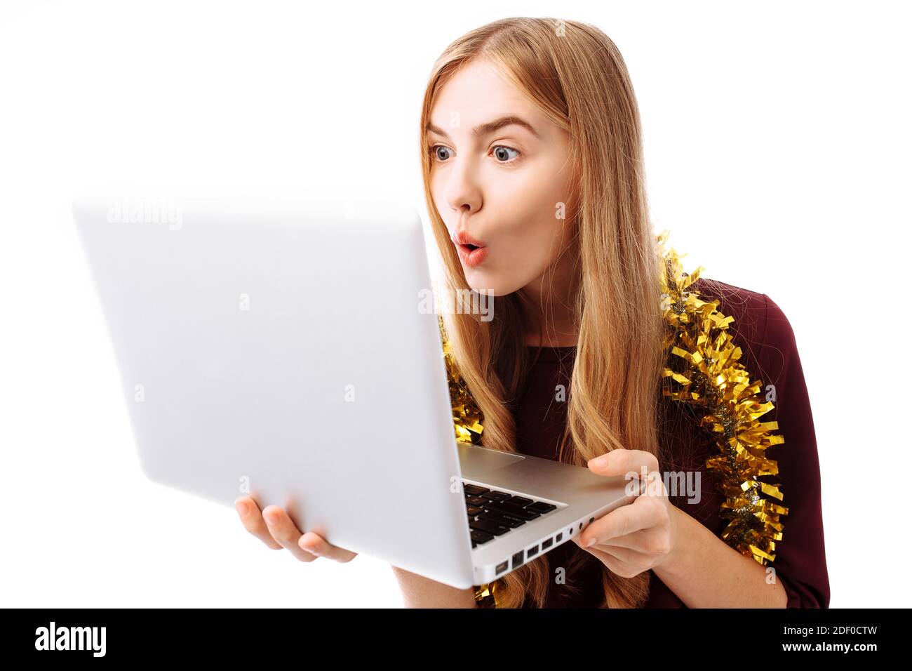 Schockiert, nutzt das Mädchen im roten Kleid den Laptop und schaut überrascht auf den Laptop-Bildschirm, auf weißem Hintergrund. Stockfoto
