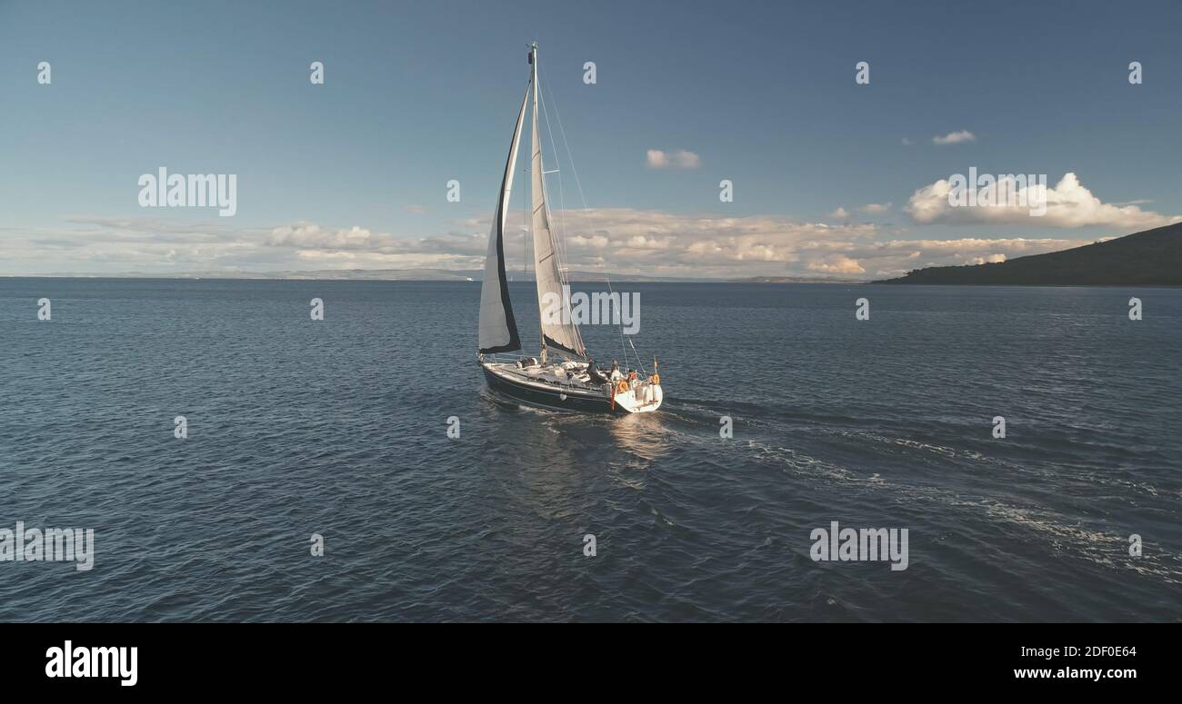 Luxus-Yacht segelt in Ocean Bay Aerial. Passagier Segelboot Rennen auf offener See in der Nähe von Arran Island, Schottland, Europa. Epische Sommerkreuzfahrt auf dem Boot bei filmischer Drohne mit sanftem Licht Stockfoto