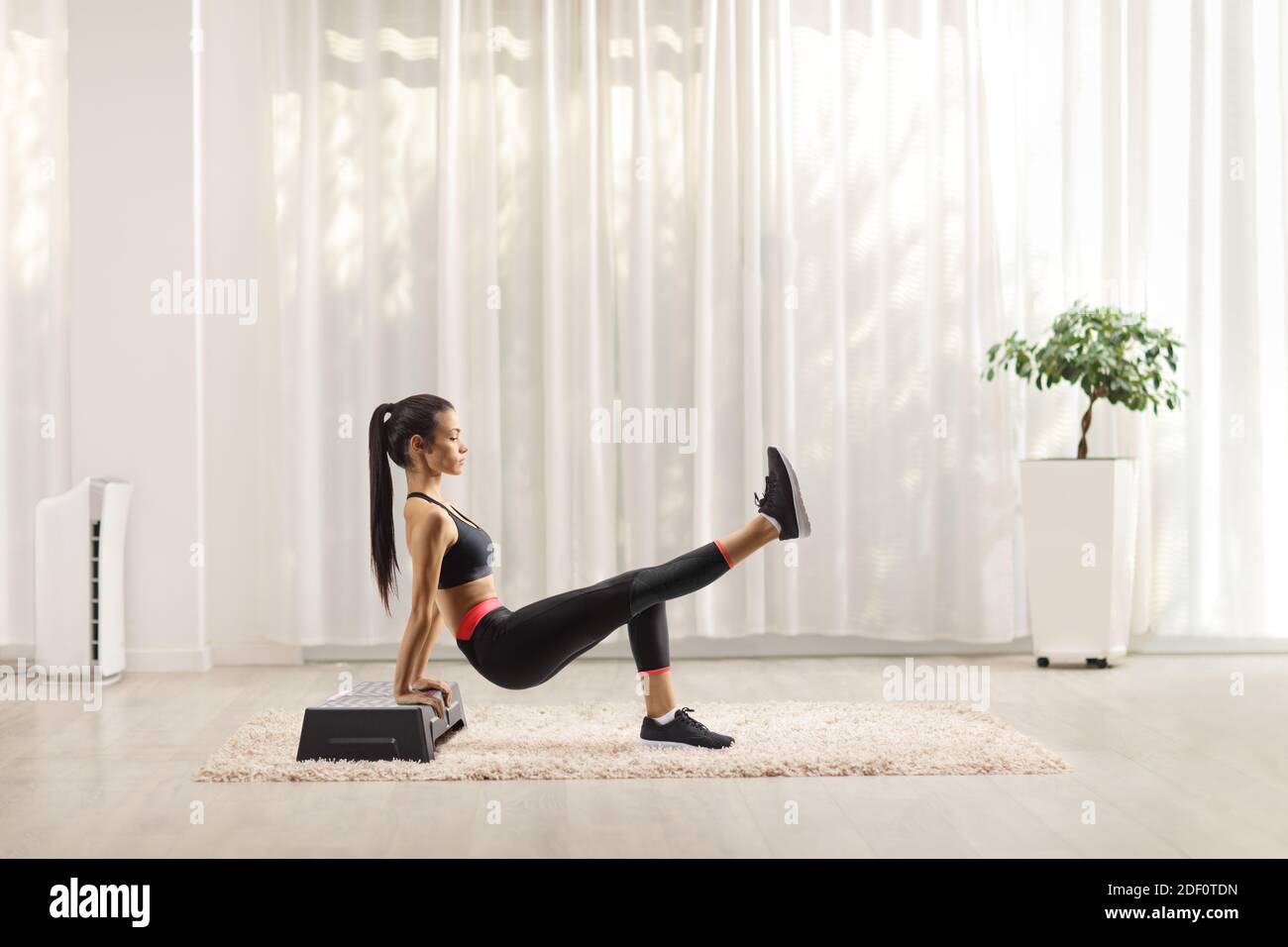 Junge Frau macht Übungen auf einem Stepper zu Hause Stockfoto