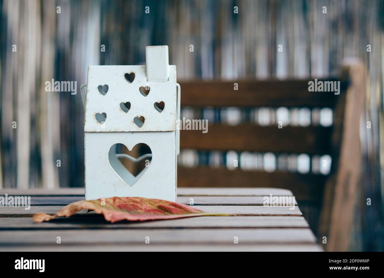 Eine weiche Fokusaufnahme einer hausförmigen Laterne mit Herzlöcher auf einem Holztisch Stockfoto