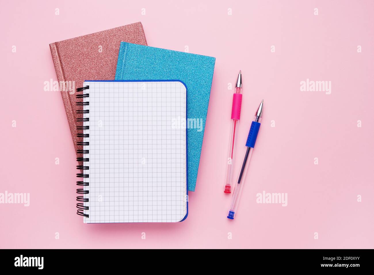 Spiral Notizblock mit Stiften als Mockup für Ihr Design. Notizbücher auf pastellrosa Hintergrund. Zurück zur Schule Konzept. Platz kopieren, Draufsicht. Stockfoto