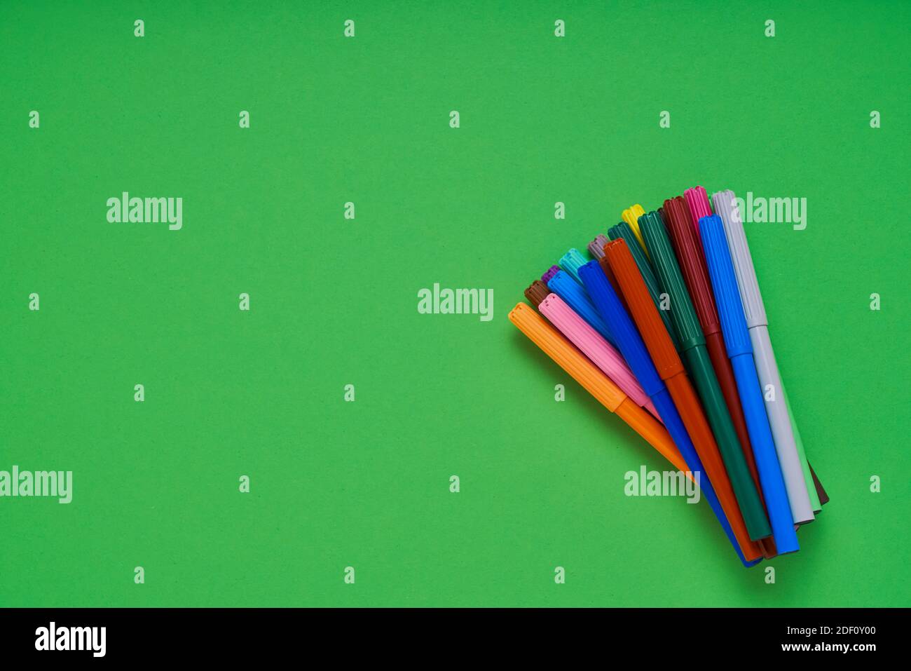 Farbige Filzstifte auf neongrünem Hintergrund mit Platz für Text. Draufsicht. Minimalismus Stockfoto