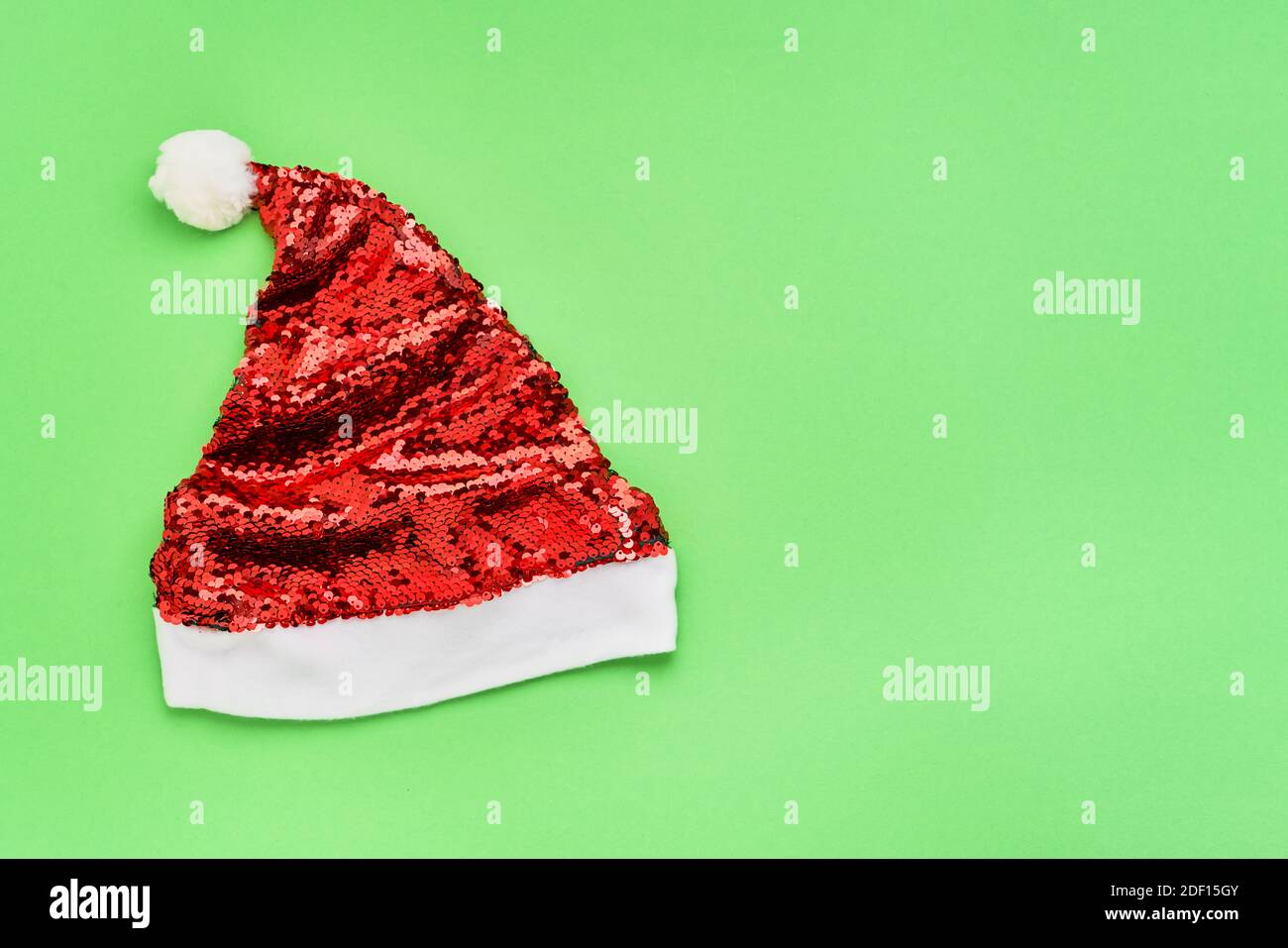 Rot funkelnden Weihnachtsmann Hut auf einem grünen Hintergrund. Weihnachtsfeier Konzept. Flach liegend, Platz für Text. Stockfoto