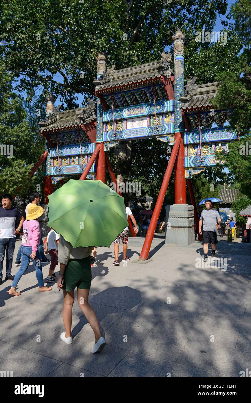 Viele Besucher gehen unter einem traditionellen Tor auf dem Gelände des Sommerpalastes im Nordosten von Peking, China Stockfoto