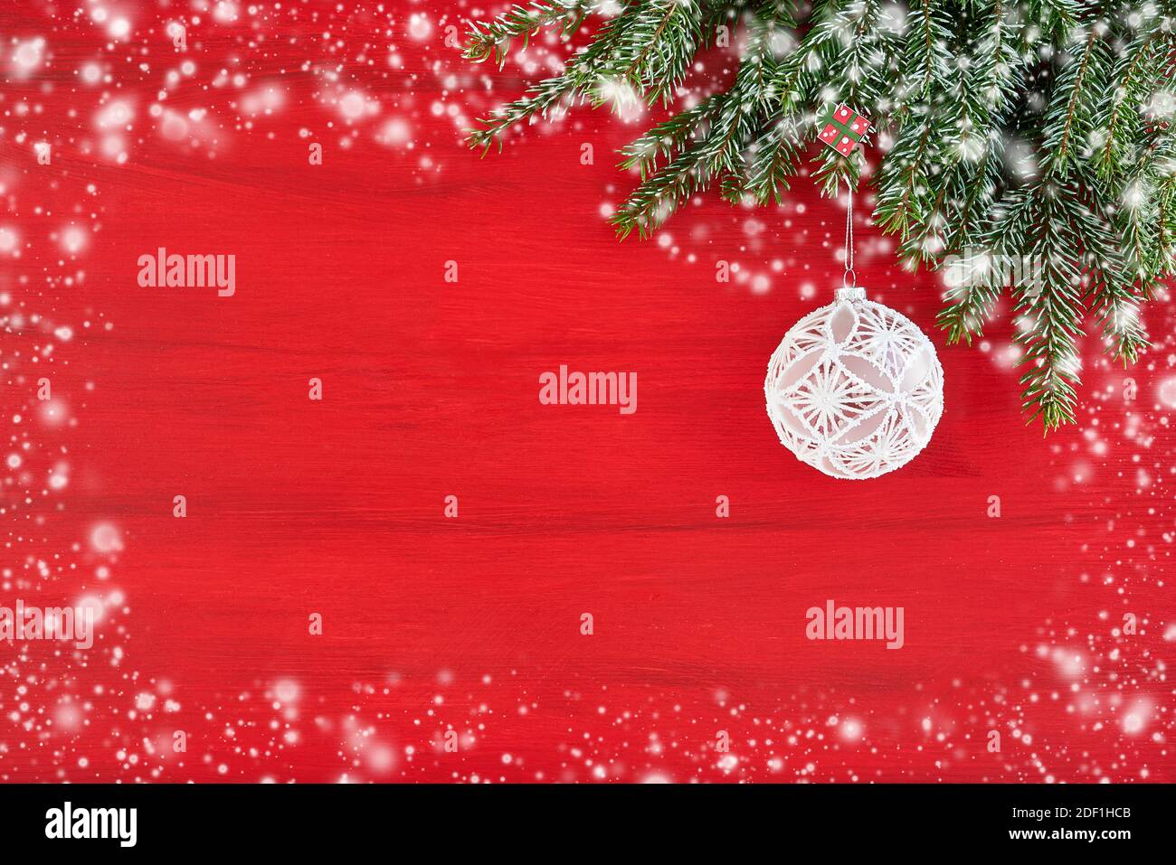 Roter Weihnachtshintergrund mit Tannenzweig und weißen Weihnachtsornamenten. Speicherplatz kopieren. Weihnachtskarte Stockfoto