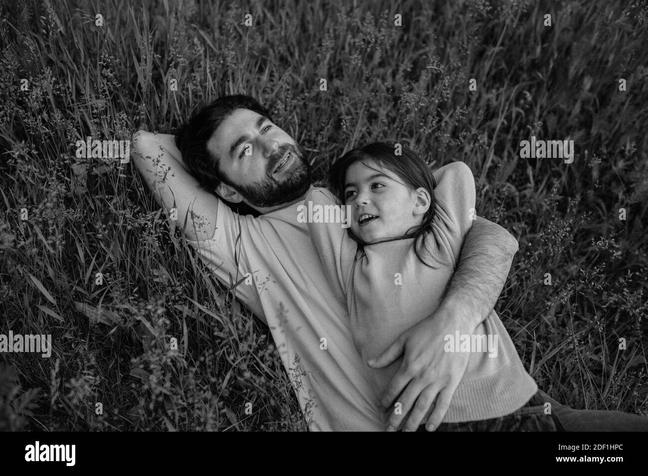Vater und Tochter legen das Gras lächelnd Stockfoto