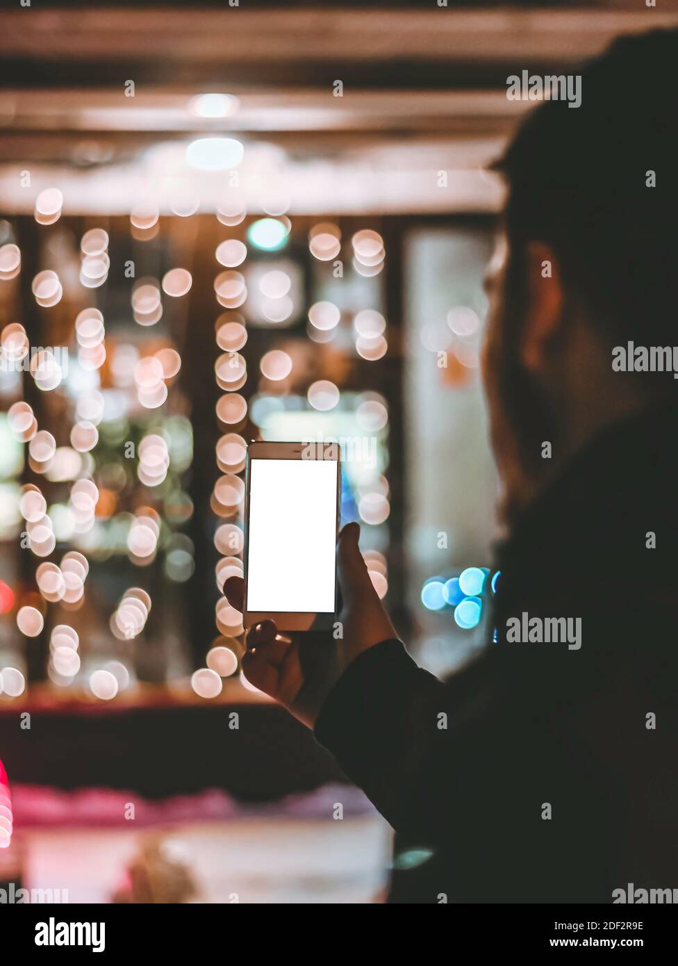 Mann hält Handy vor festlicher Weihnachtskulisse. Mobile Software-Werbung, Bildschirmfläche für Design und Text Stockfoto