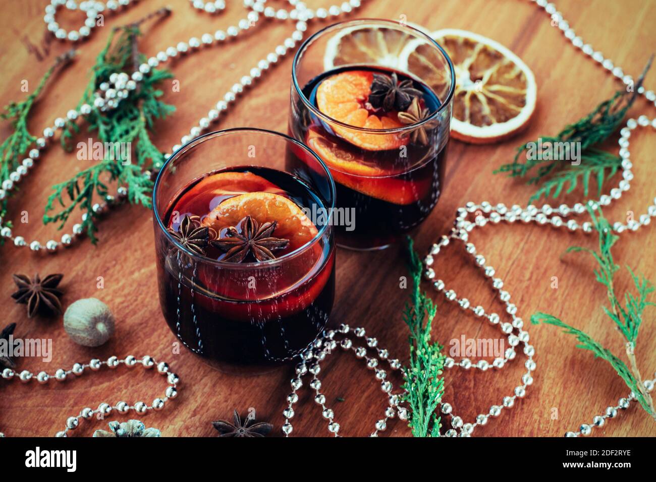 Zwei Gläser Glühwein mit Zitrusfrüchten, Sternanis, Muskatnuss auf Holztisch. Weihnachtliches Glühgetränk, Neujahrsdekoration, Draufsicht. Stockfoto