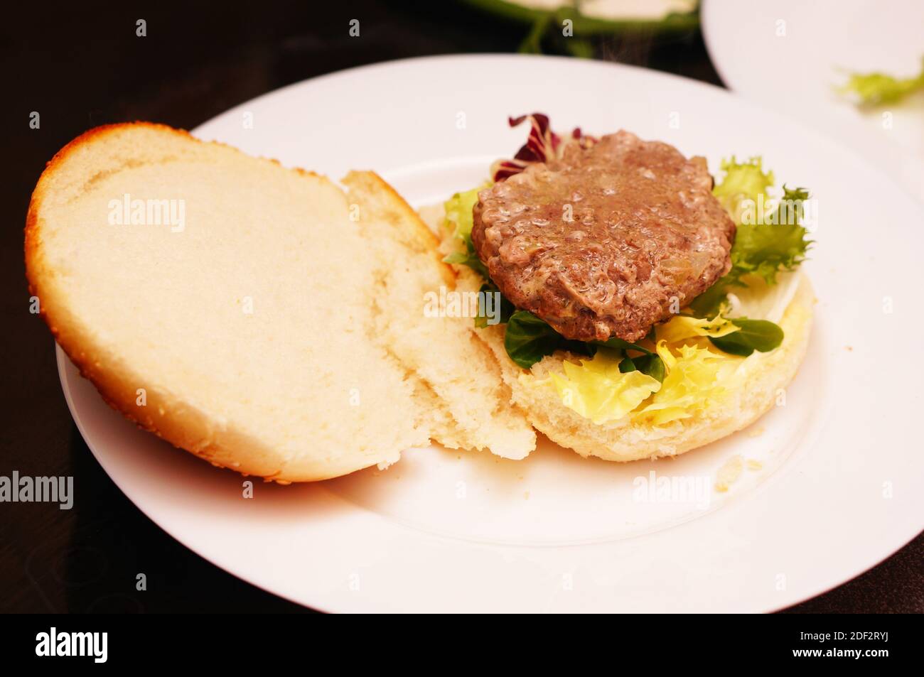 Das Brötchen des Burgers wartet darauf, angesetzt zu werden Das Patty Stockfoto