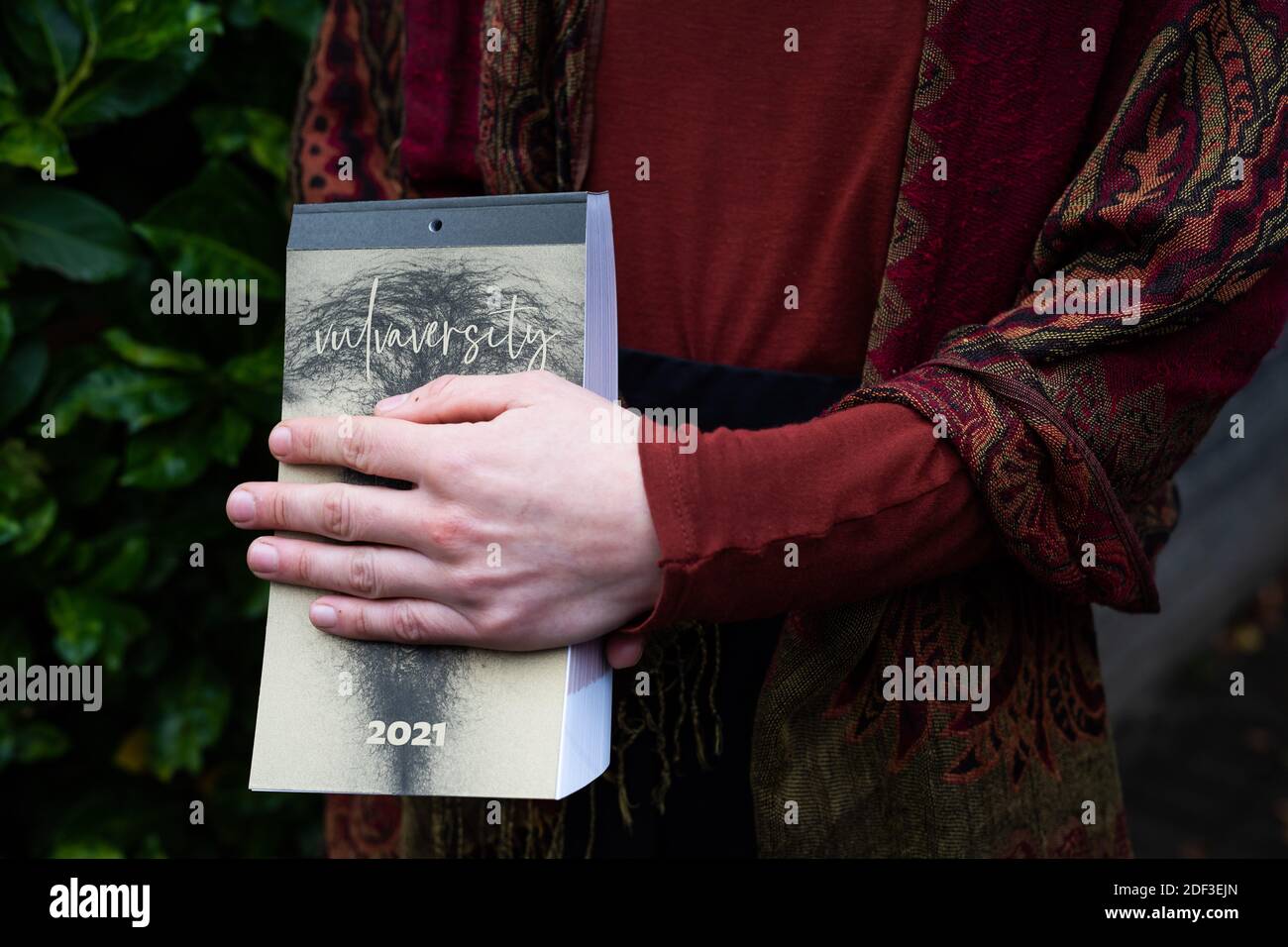 Freiburg, Deutschland. November 2020. Ein Mitglied des Freiburger Kollektivs Vulvaversity hält einen ihrer Kalender in der Hand und deckt Teile davon ab. Das Freiburger Kollektiv Vulvaversity hat einen Kalender für 2021 mit 365 Vulvaren veröffentlicht. Das Projekt soll dazu beitragen, Scham und Vorurteile zu reduzieren. (To dpa: '365 Vulves - Freiburg Group publishs enlightening calendar') Quelle: Philipp von Ditfurth/dpa/Alamy Live News Stockfoto