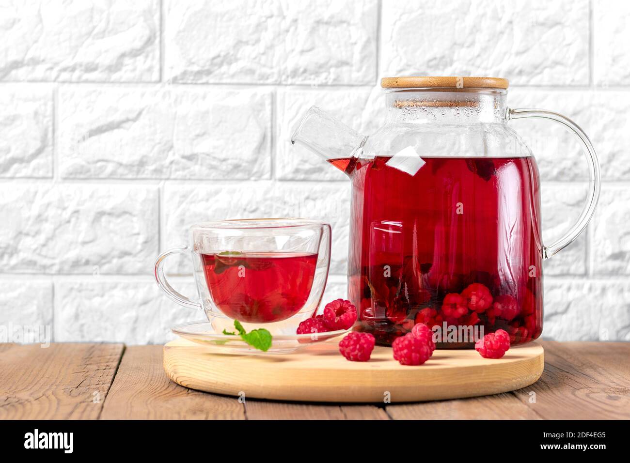 Kräutertee mit Beeren, Himbeeren, Minzblättern und Hibiskusblüten in Glas Teekanne und Tasse auf Holztisch Medizin für kaltes Vitamin Drink Rustikal Stockfoto