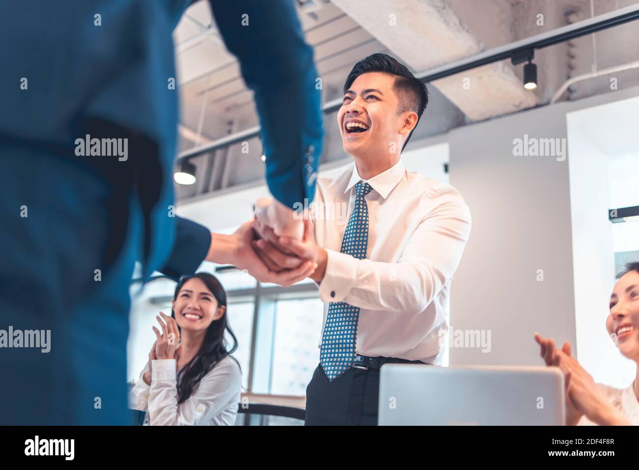 Glückliche Geschäftsleute, die sich im Konferenzraum die Hände schütteln Stockfoto