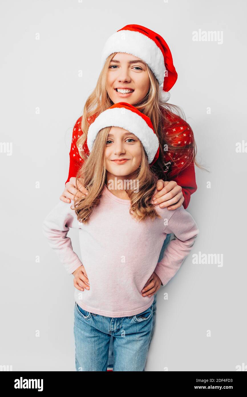 Mama und Tochter tragen Weihnachtsmann-Hüte, und in Weihnachten umarmen sich Pullover. Auf weißem Hintergrund. Das Konzept einer starken Familie. Stockfoto