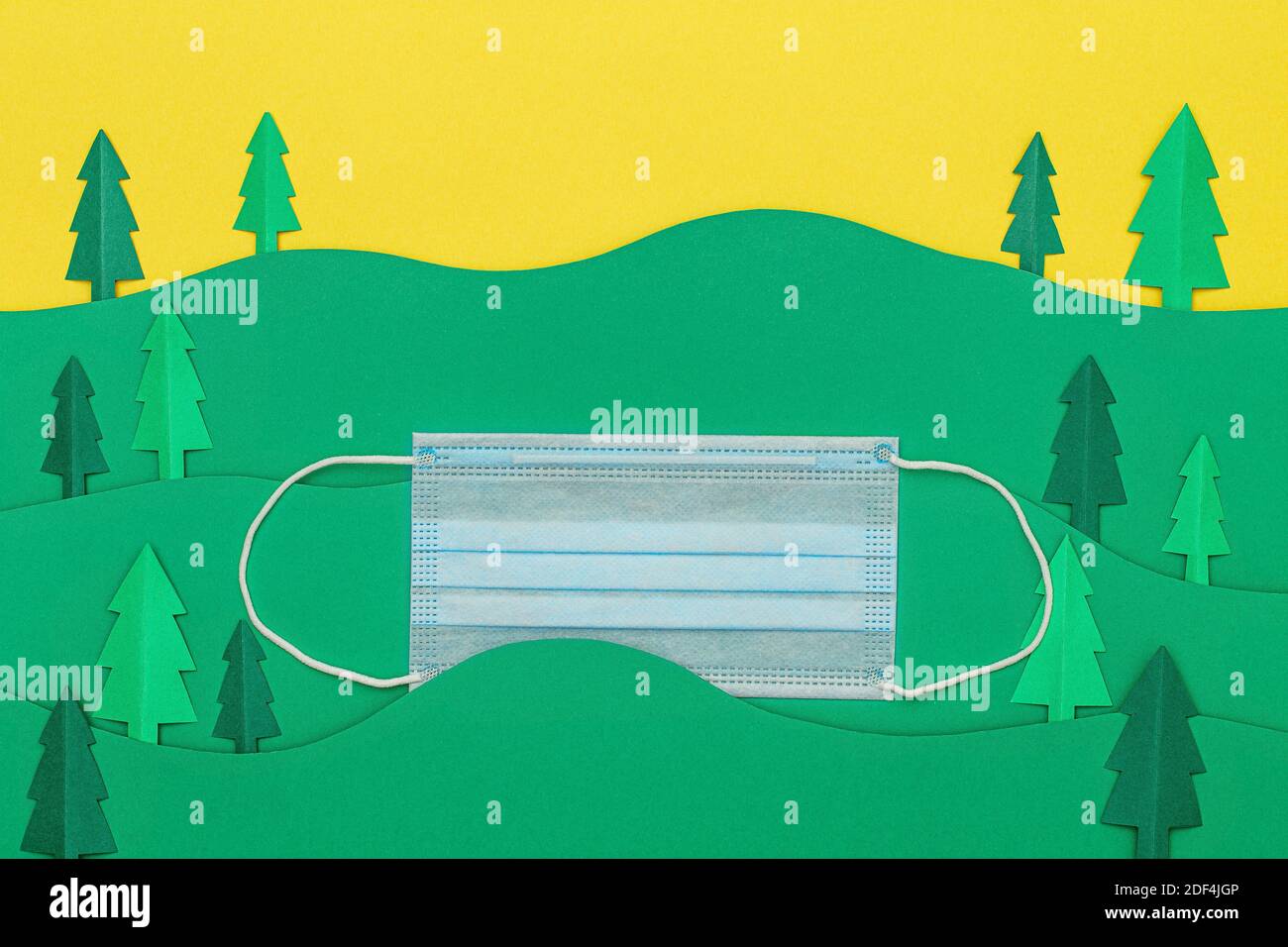 Weihnachtsbäume aus Papier mit medizinischen Einweg-Gesichtsmaske auf grünem Hintergrund geschnitten. Weihnachtsbaum Papier schneiden Design-Karte. Draufsicht. Flach liegend Stockfoto