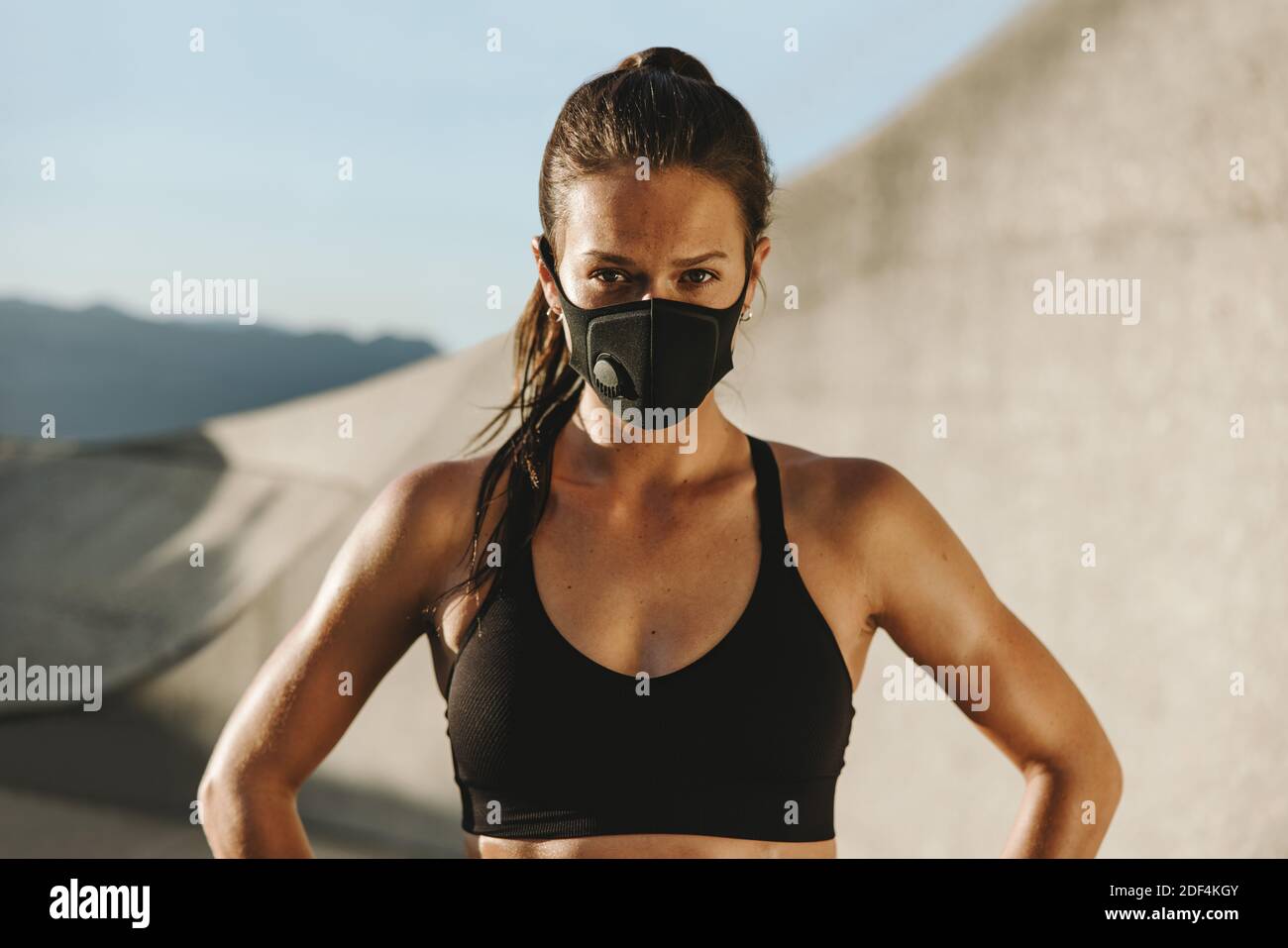 Fitness-Frau in Sportbekleidung und Gesichtsmaske. Frau in Schutzmaske, die in die Kamera schaut. Stockfoto