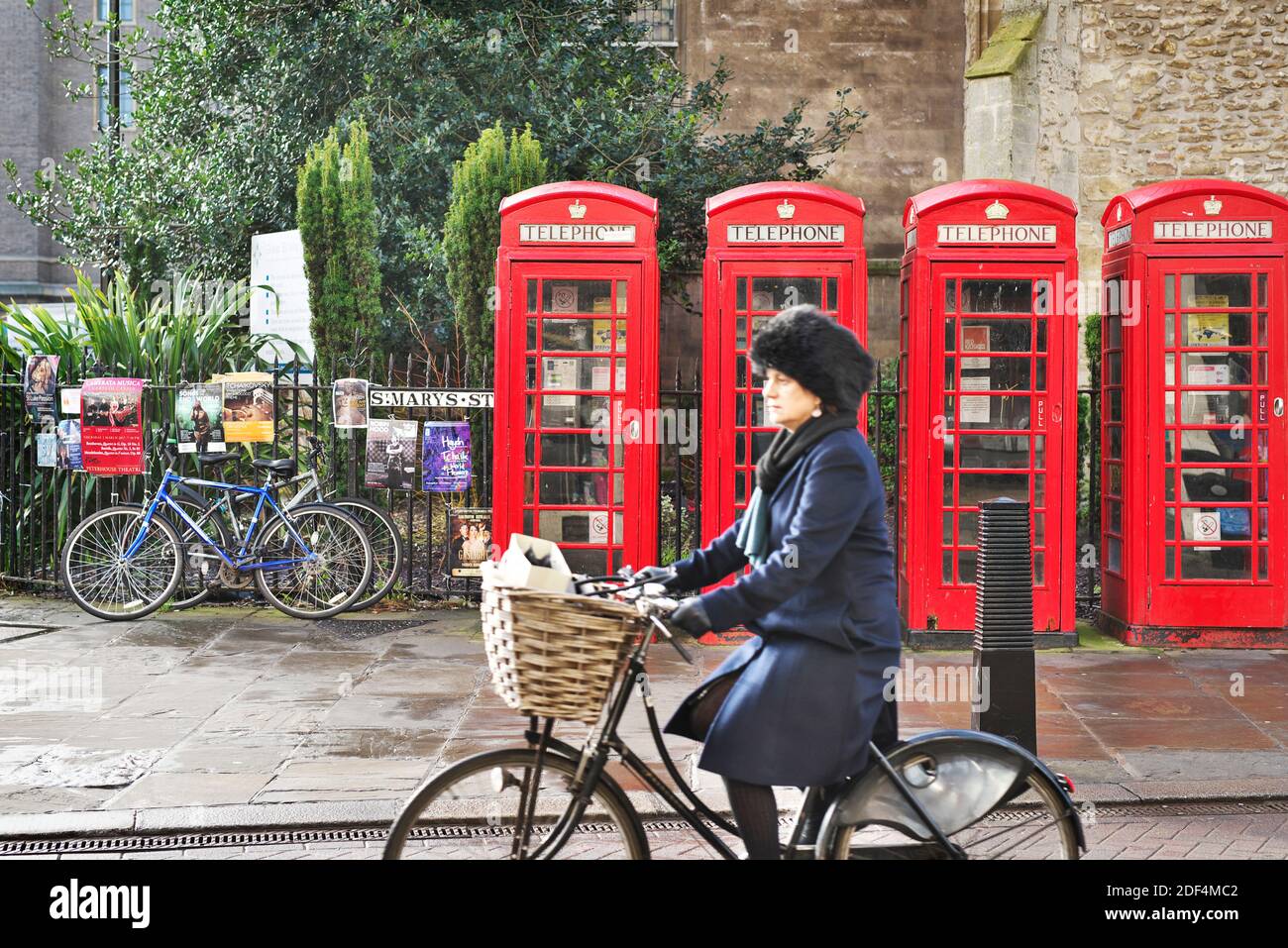 Lady radelt in Cambridge, Großbritannien, an roten Telefonzellen vorbei Stockfoto