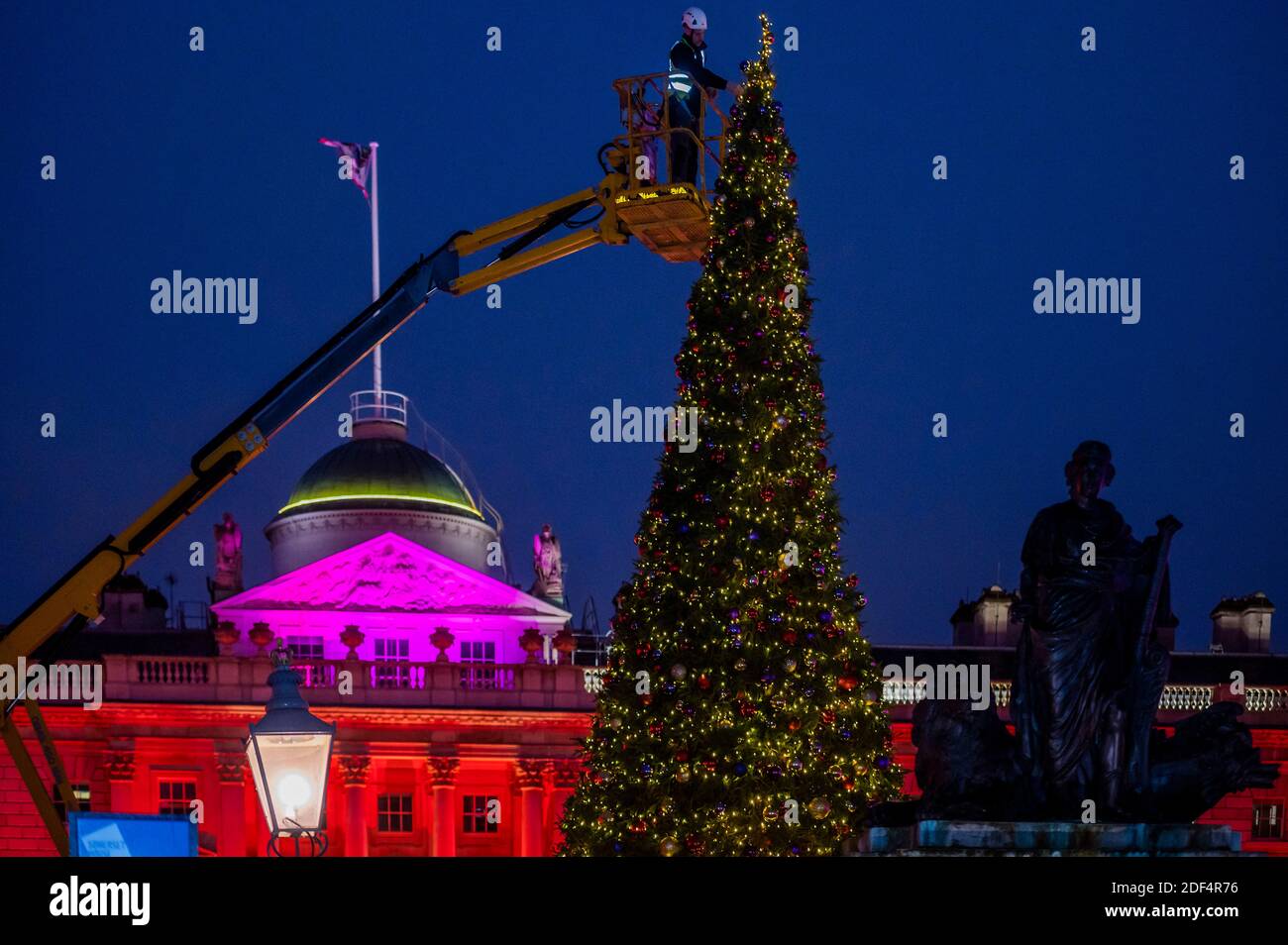 London, Großbritannien. Dezember 2020. Somerset House fügt die endgültige Dekoration zu seinem 40 Fuß Weihnachtsbaum vor der Wiedereröffnung, nach dem Ende der zweiten Coronavirus-Sperre, am Donnerstag, 3. Dezember. Neben dem Baum können die Besucher des Londoner Kunstgewerbezentrums im neoklassizistischen Innenhof Pop-up-private Dining-Kuppeln nutzen und so ein neues festliches Gourmet-Erlebnis schaffen. Kredit: Guy Bell/Alamy Live Nachrichten Stockfoto