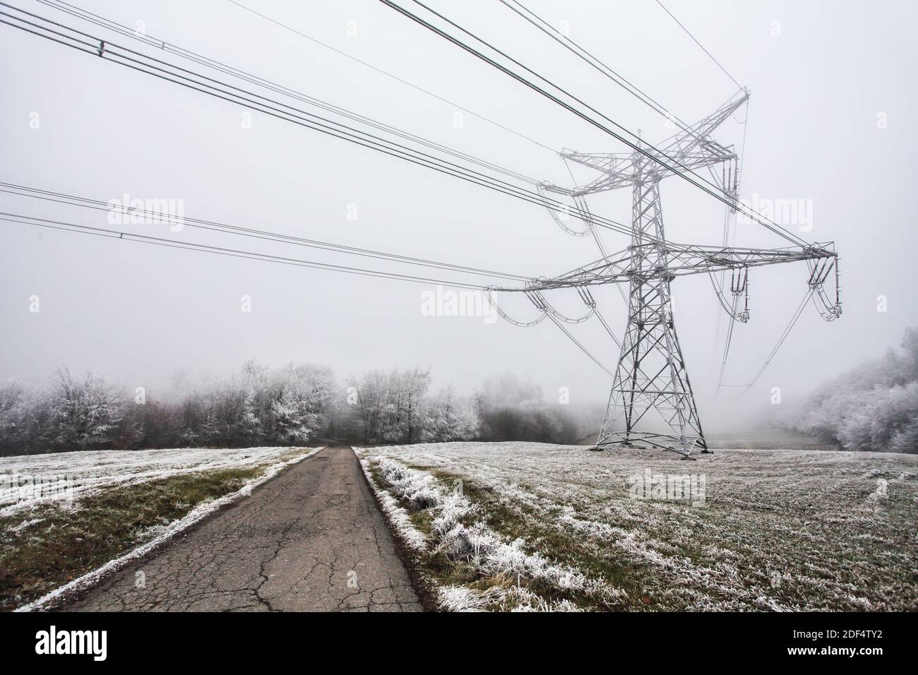 Elektrischer Mast im Winter mit Straße im Berg Stockfoto