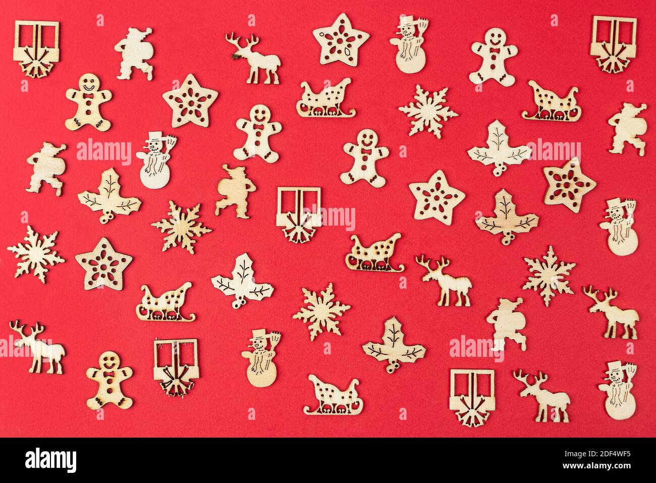 Eine Textur, die von kleinen hölzernen Weihnachts-Ikonen auf einem gebildet wird Roter Hintergrund Stockfoto