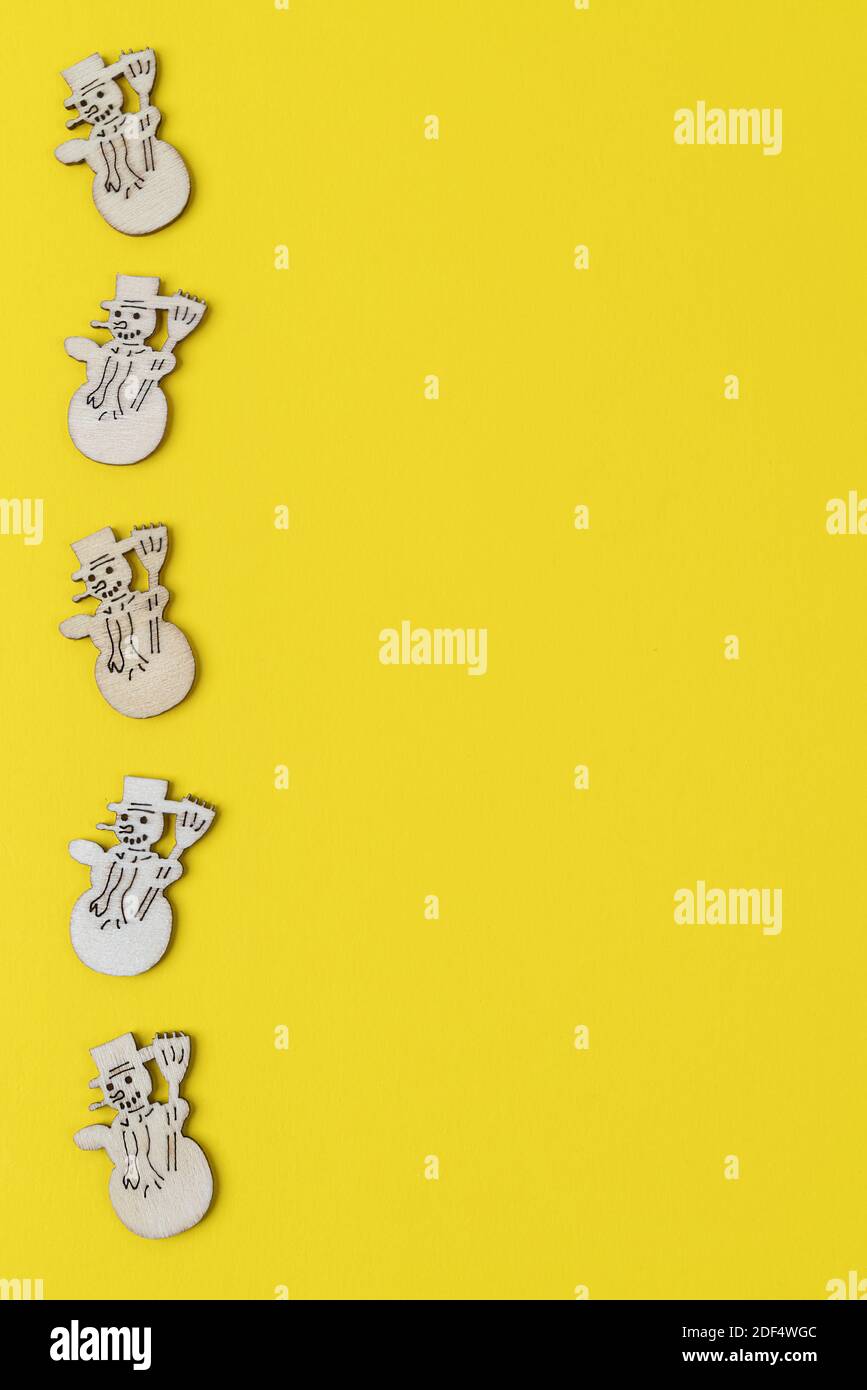 Eine Reihe von kleinen Figuren von hölzernen Schneemännern auf einem Gelber Hintergrund Stockfoto