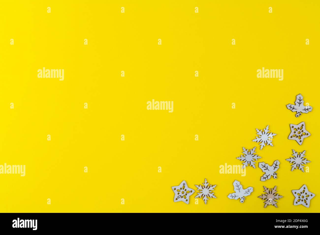 Eine Textur, die von kleinen hölzernen Weihnachts-Ikonen auf einem gebildet wird Gelber Hintergrund Stockfoto