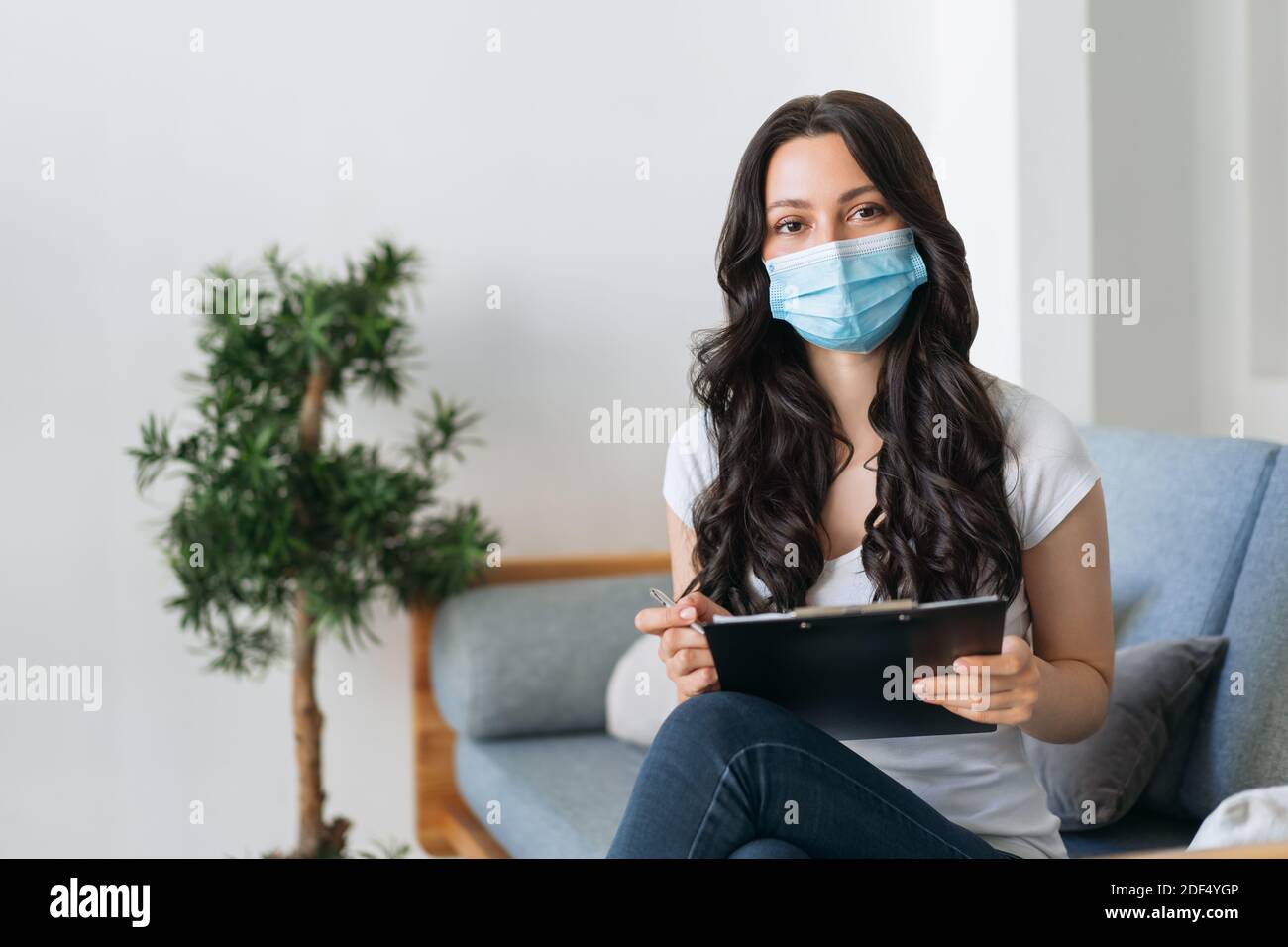 Frau in medizinischer Maske Ausfüllen eines Fragebogens Stockfoto