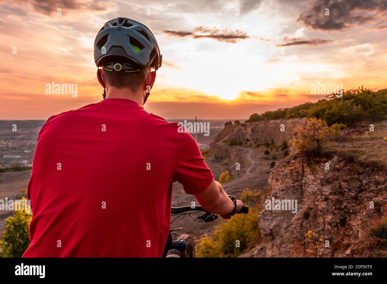 Rückaufnahme von Mountainbiker bei Sonnenuntergang mit modernem Fahrradhelm. Stockfoto