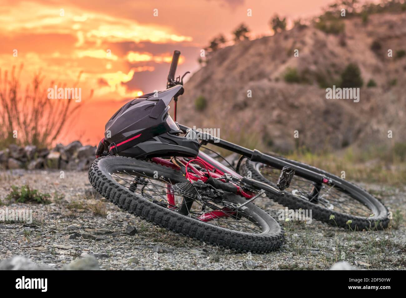 Rückaufnahme des Downhill-Bikes mit schwarzem Integralhelm bei Sonnenuntergang. Stockfoto