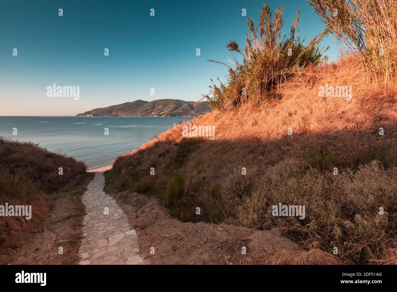 Kopfsteinpflasterperspektive, Steintreppen gehen zum Strand in der Morgensonne hinunter Stockfoto