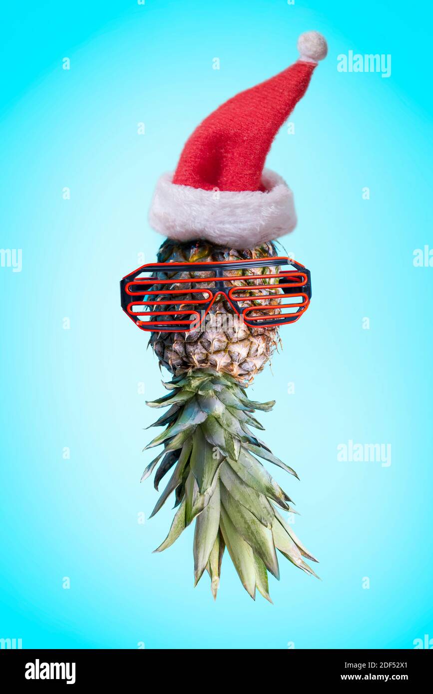 Santa Ananas. Funky Pop Art minimal weihnachten im Sommer Konzept. Lustige Ananas mit Sonnenbrille und weihnachtsmann Hut auf hellem pastellfarbenem Hintergrund. Cool Stockfoto