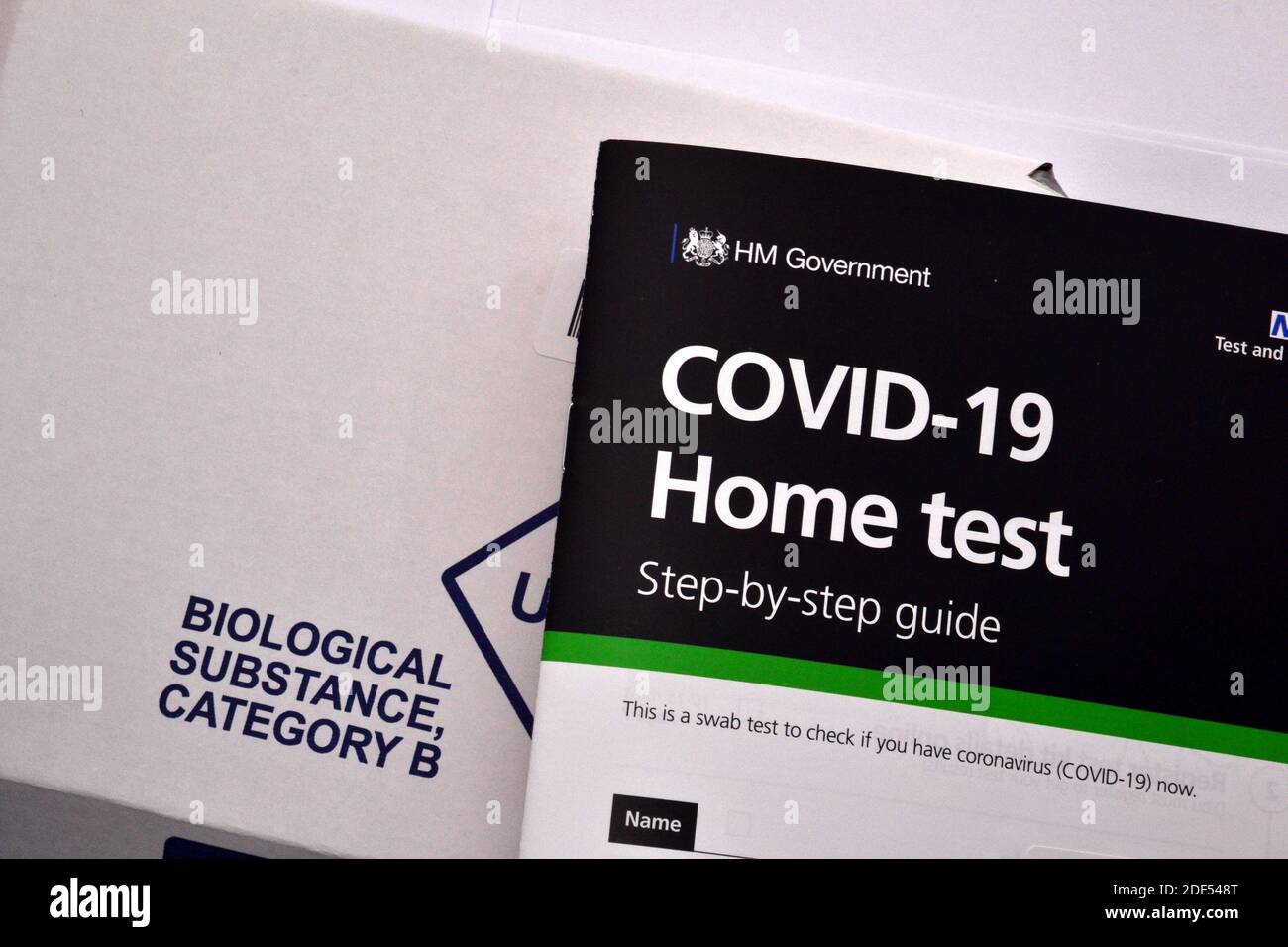 Eine britische H M Government und NHS Covid 19 Home Test Instruction Booklet auf dem Karton mit der Aufschrift "Biological Substance" für die Rückgabe der Testprobe. Stockfoto