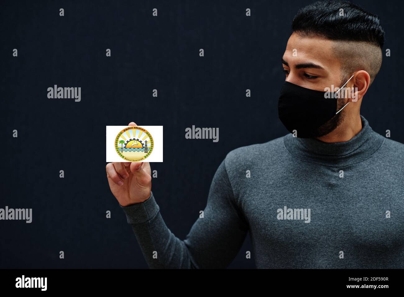 Ägyptischer Mann in grau Rollkragen und schwarze Gesichtsschutz Maske zeigen Matruh Flagge isoliert Hintergrund. Gouvernements von Ägypten Coronavirus Konzept. Stockfoto
