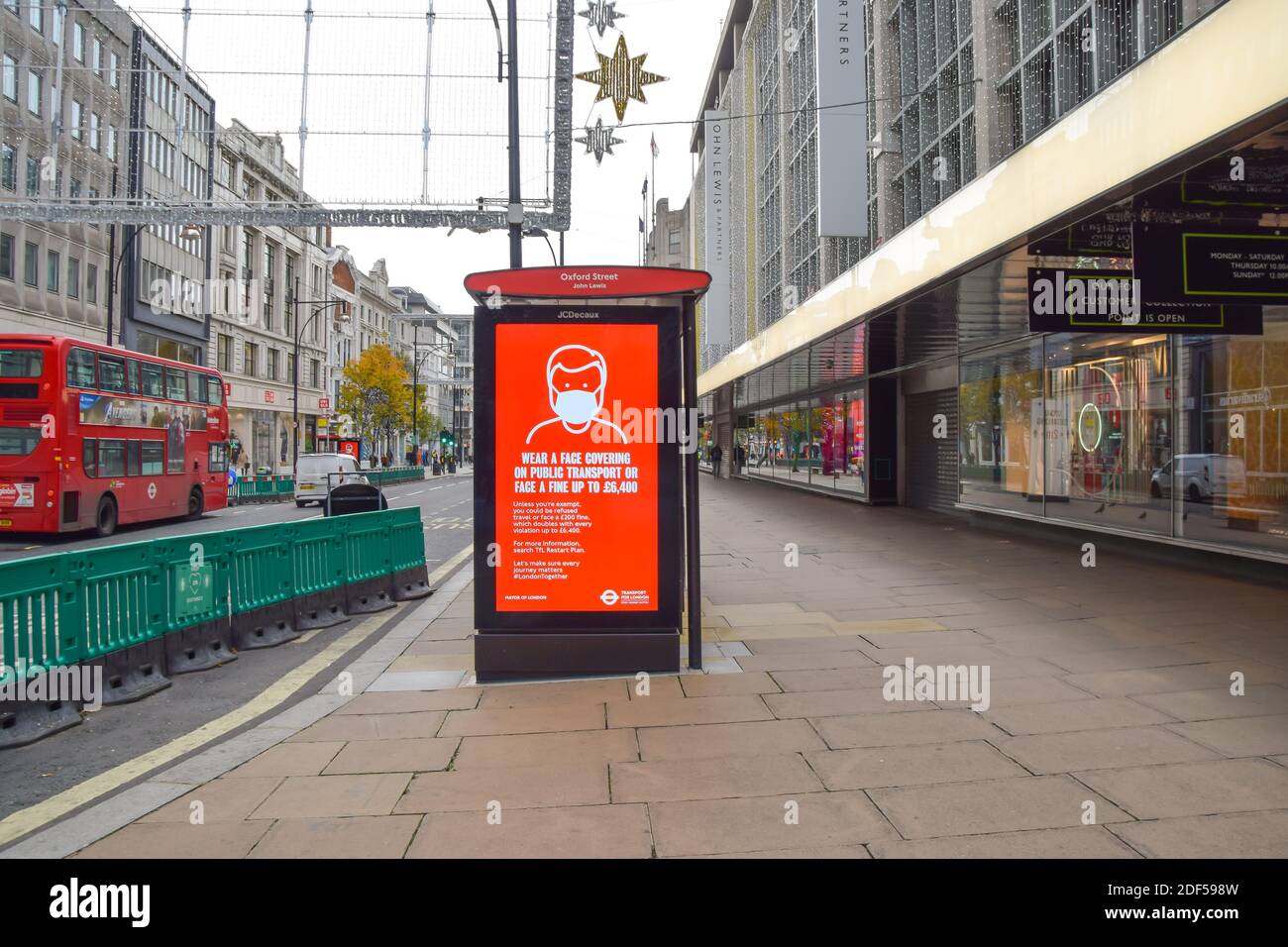 Tragen SIE an einer Bushaltestelle in der Oxford Street, London, EIN Schild mit Gesichtsbedeckung. Stockfoto