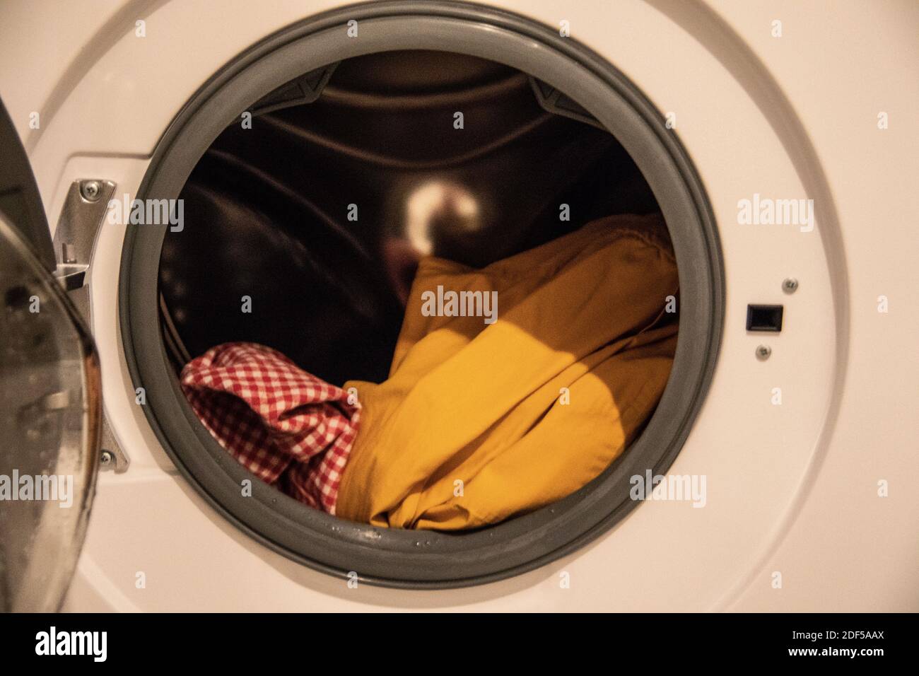 Die Waschmaschine wirbelt die Wäsche beim Waschen vor dem Bullauge Lösung Stockfoto