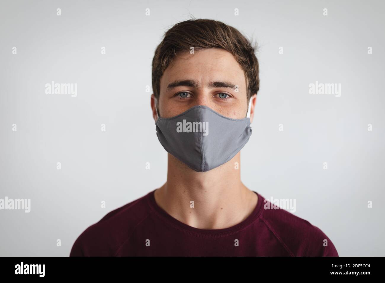 Porträt von kaukasischen Mann trägt Gesichtsmaske vor grauem Hintergrund Stockfoto