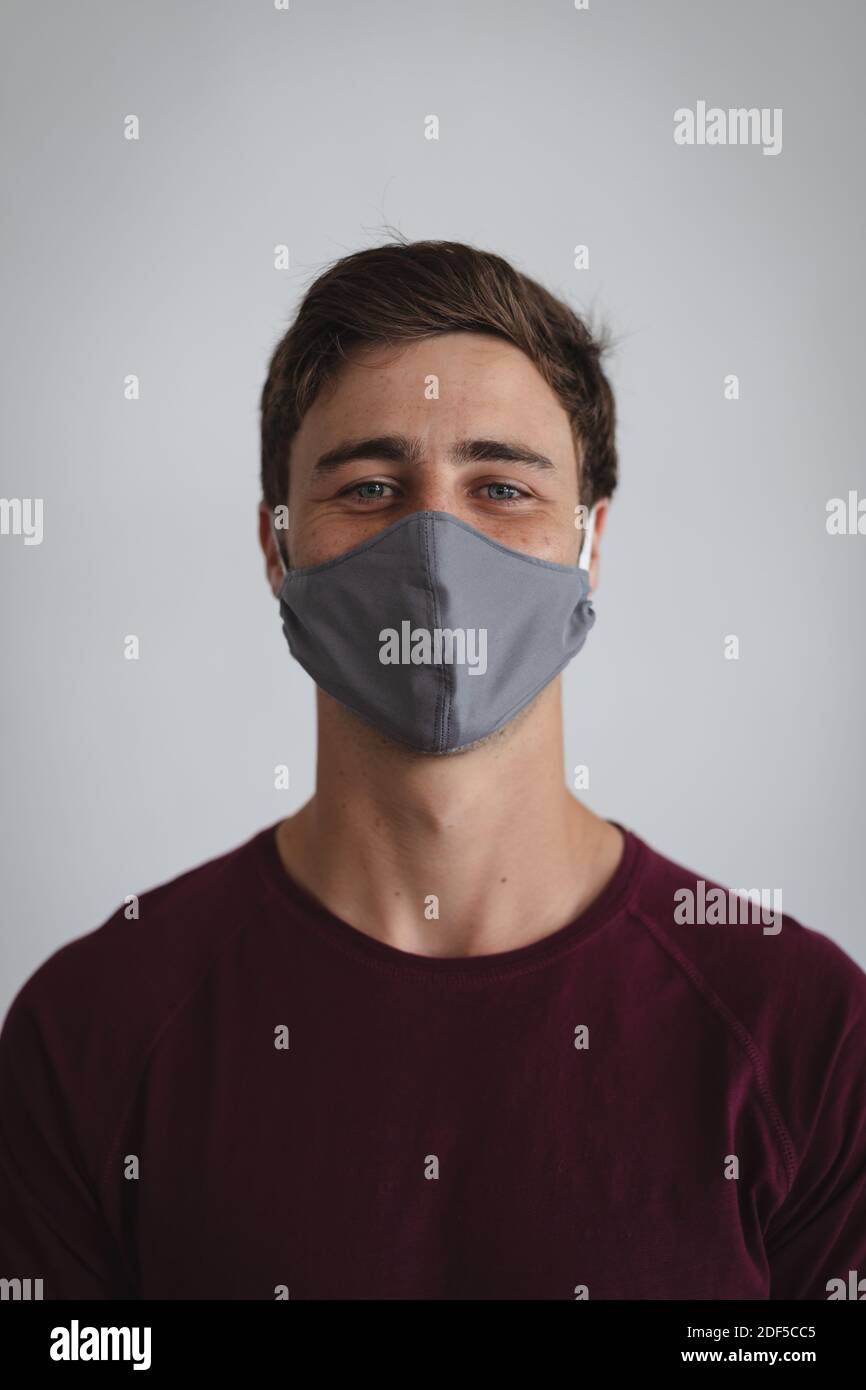 Porträt von kaukasischen Mann trägt Gesichtsmaske vor grauem Hintergrund Stockfoto