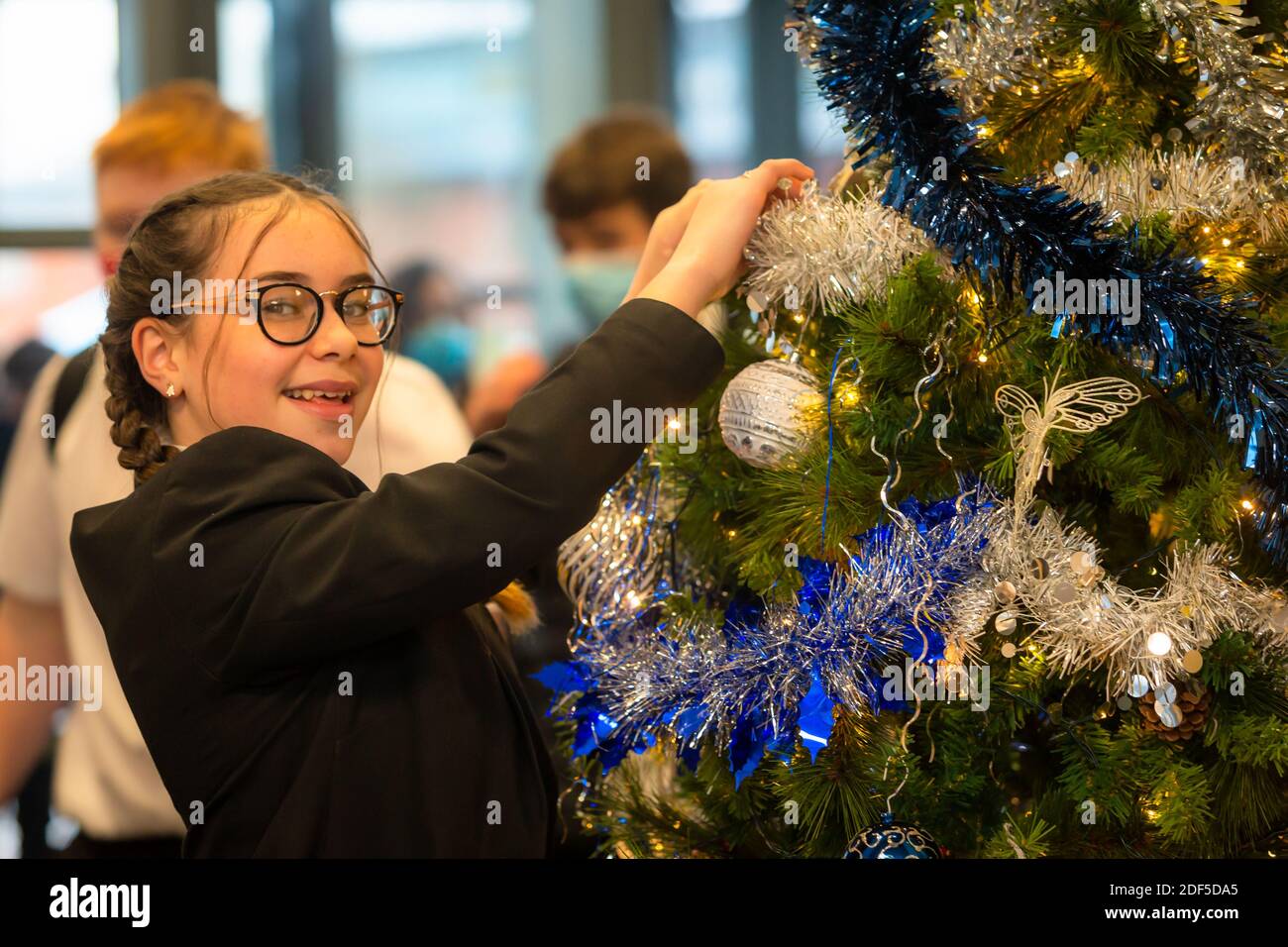 Schulschülerin, die einen Weihnachtsbaum schmückt, Großbritannien Stockfoto