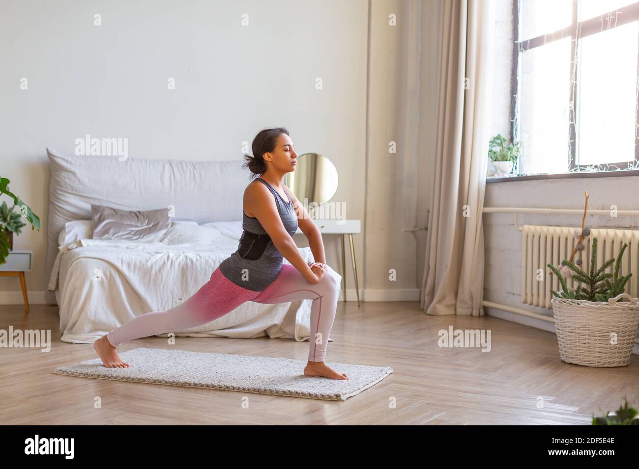 Afroamerikanische Frau macht Übung Ausfallschritte zu Hause. Foto in voller Länge. Stockfoto